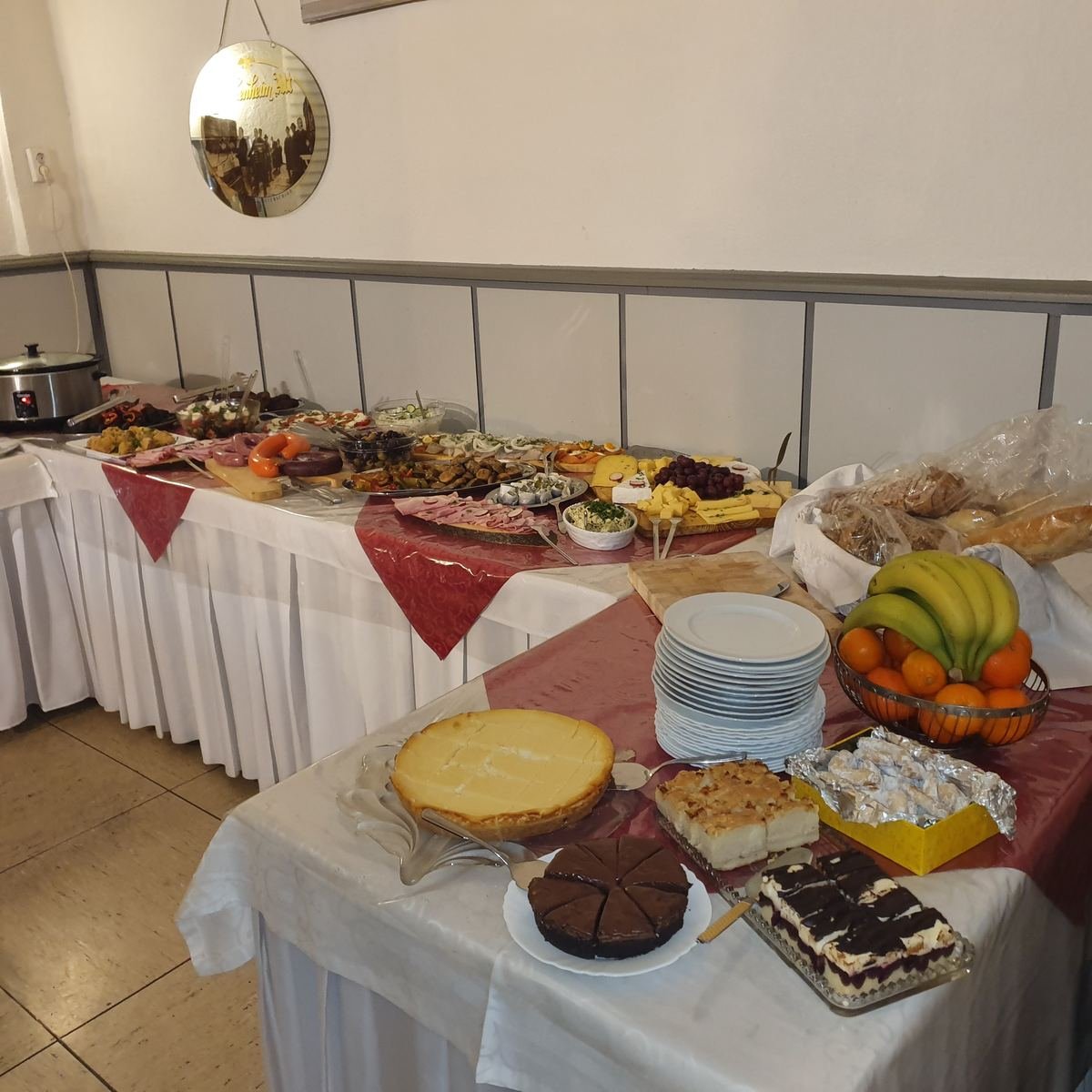Kuchen und Desserts, daneben eine Obstschale und ein Stapel Teller.