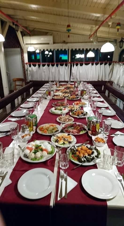Eine lange, gedeckte Tafel mit weinroten Läufern und Tellern.